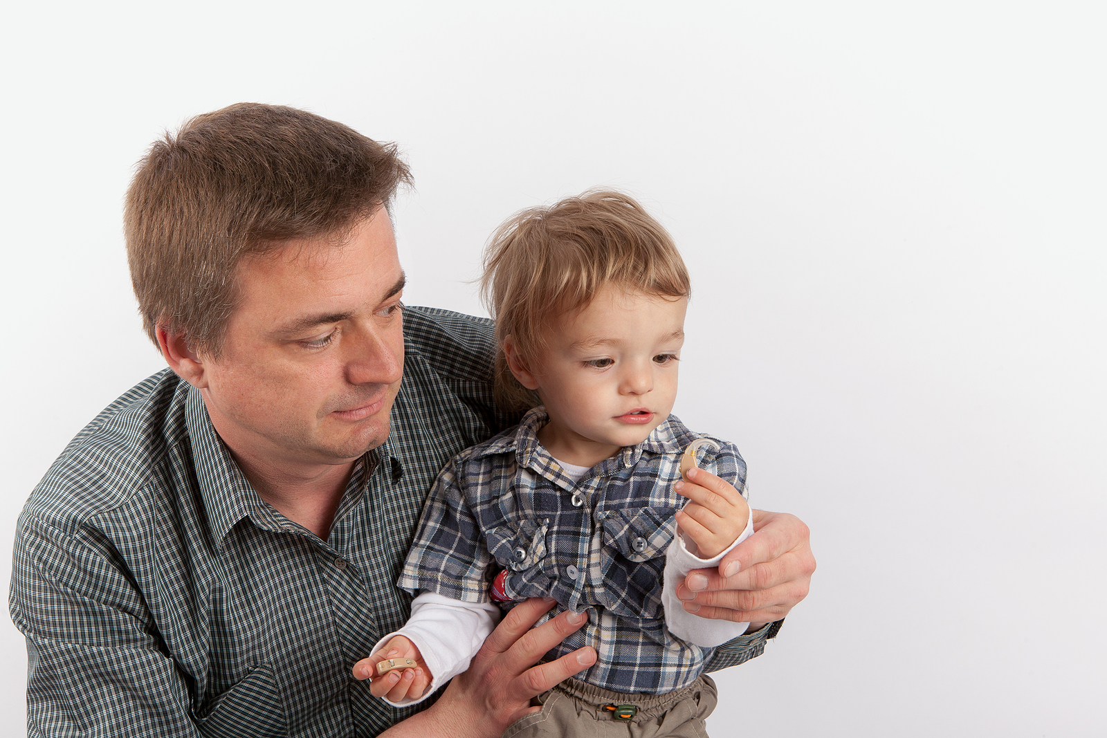 child holding hearing aid with dad